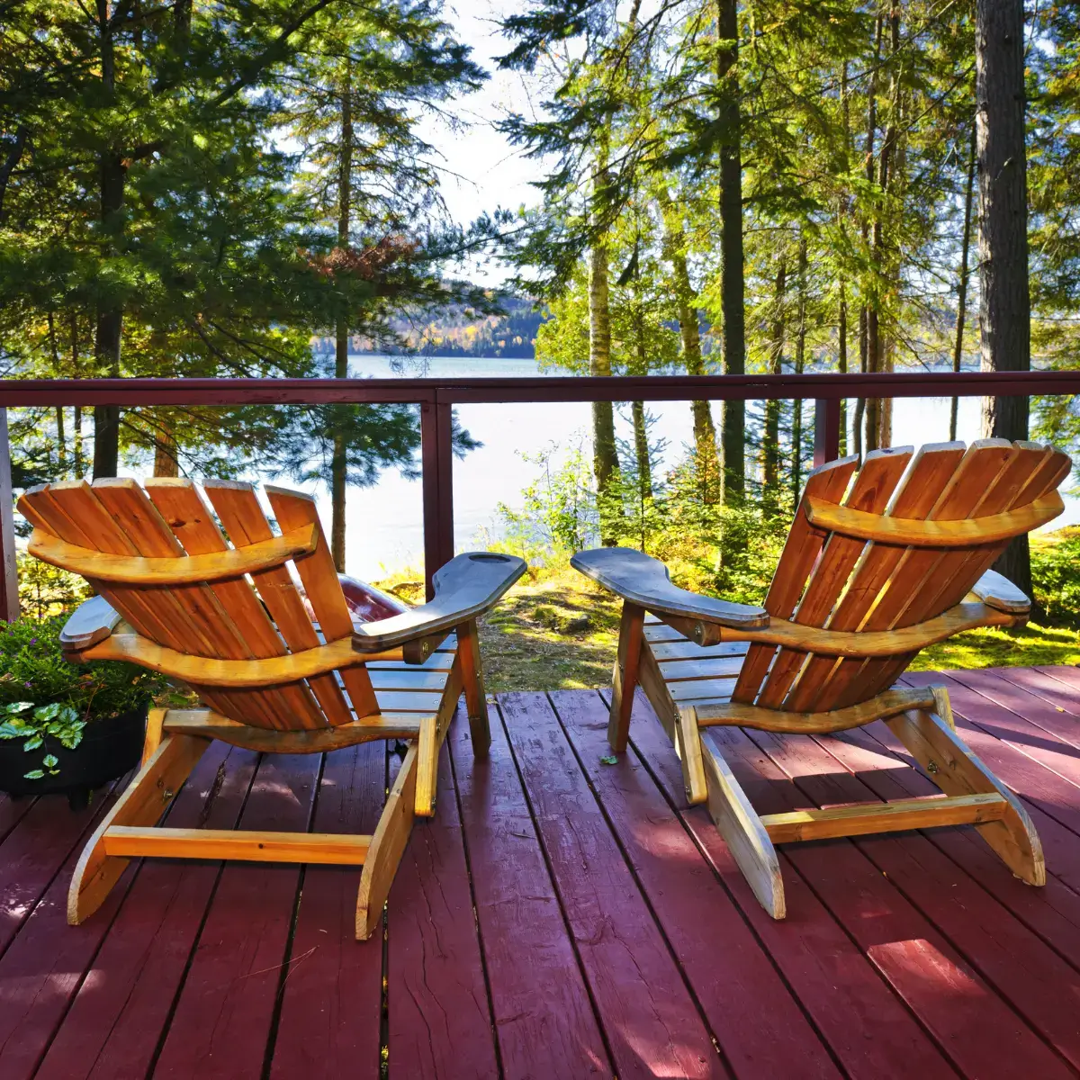 Wooden deck with Adirondack chairs overlooking a lake