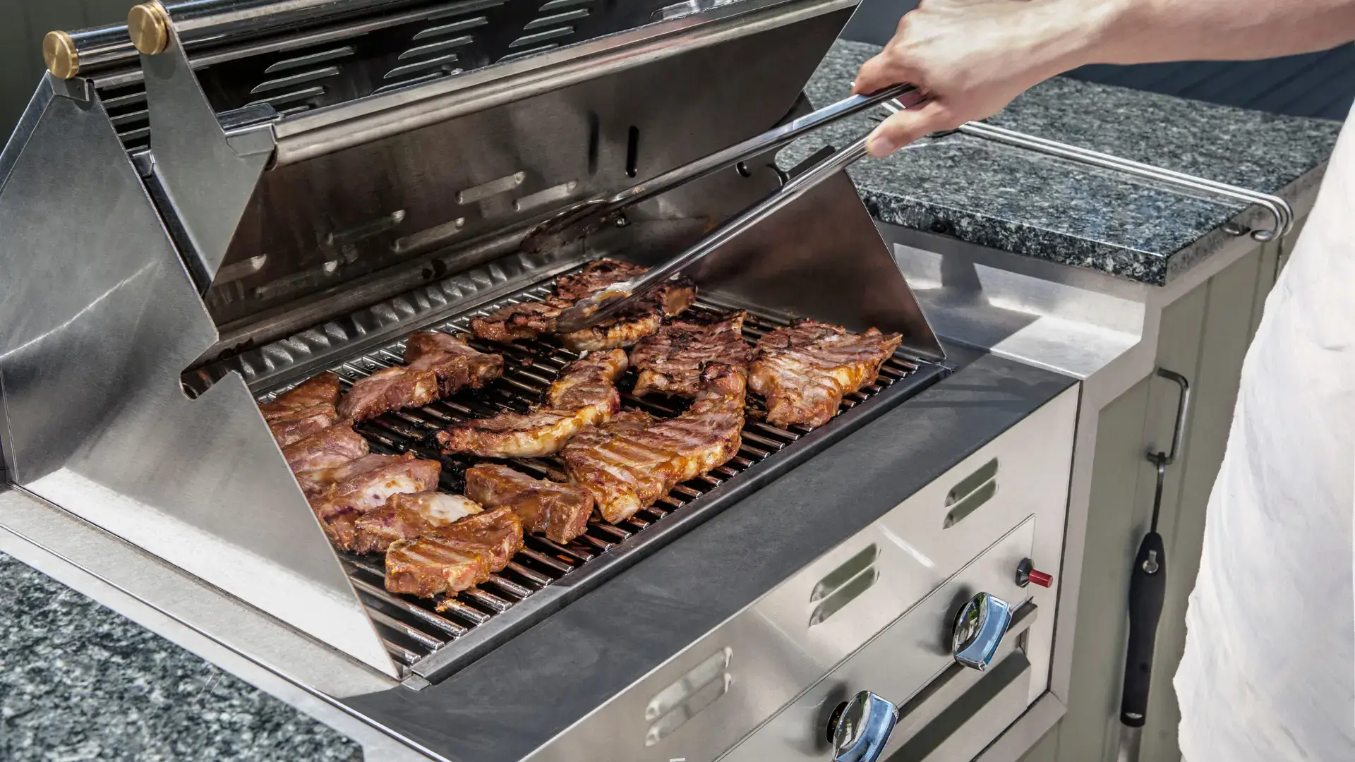 Stainless steel outdoor grill with meat cooking on the grates